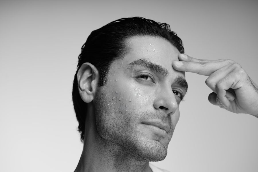 Black and white portrait of a man with slicked hair touching his temple