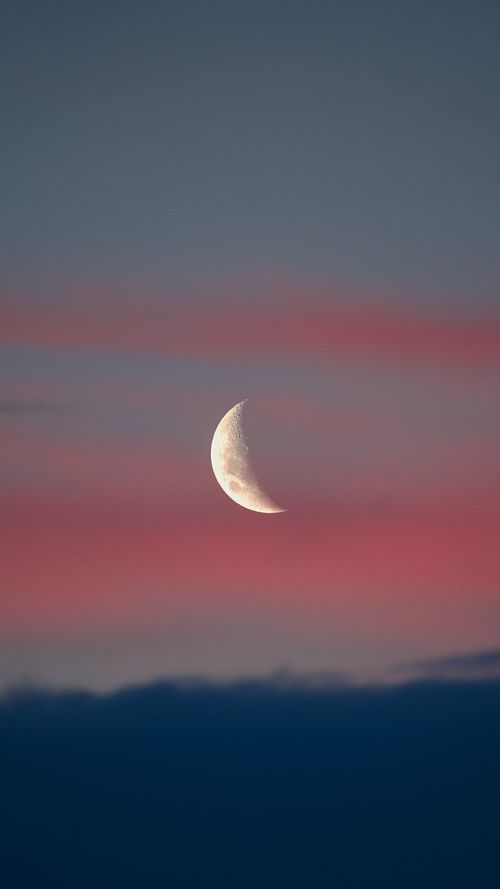 Free A serene crescent moon set against a vivid pink and blue twilight sky, creating a peaceful atmosphere. Stock Photo