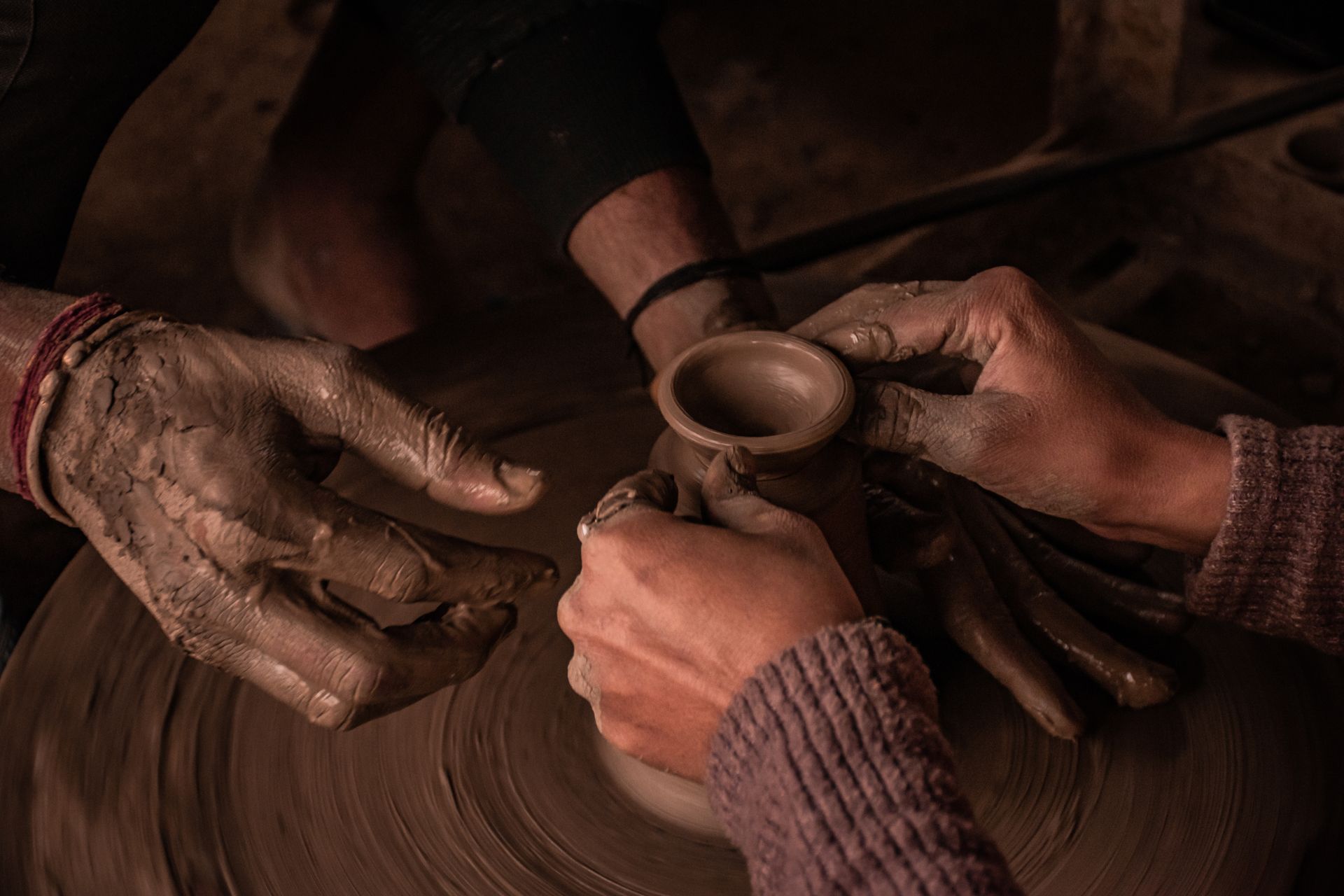 Close-up of hands crafting pottery on a wheel in Delhi, showcasing traditional Indian craftsmanship.