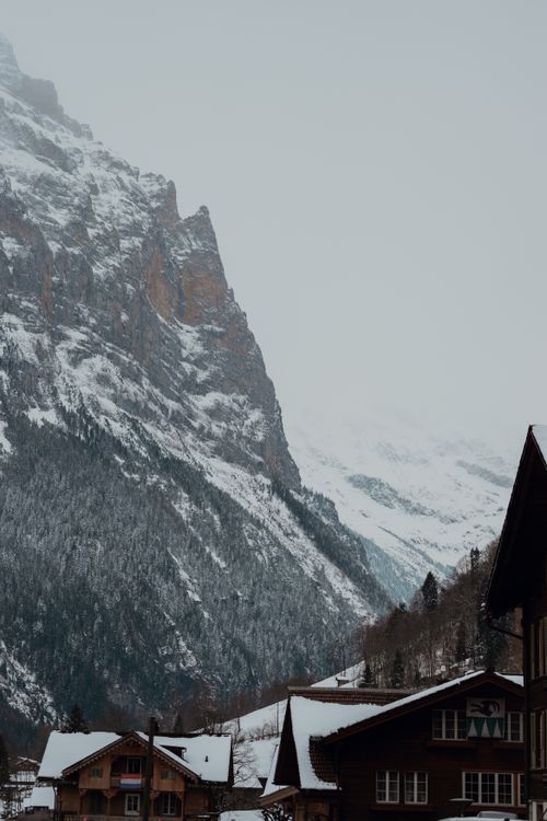 Free Majestic mountain view with snow-covered rooftops in a quaint alpine village setting. Stock Photo