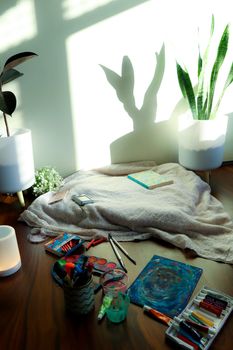 Creative art supplies set against a soft sunlight backdrop, featuring plant shadows.