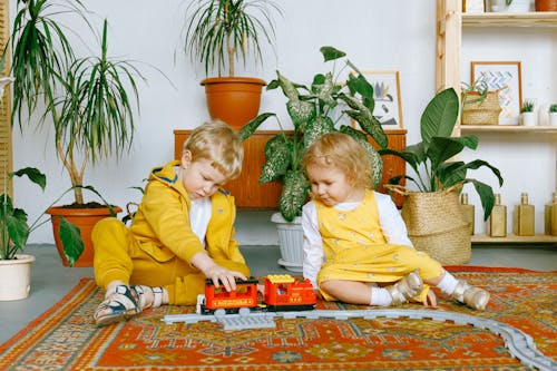 Free Adorable little boy and girl playing with toy train Stock Photo
