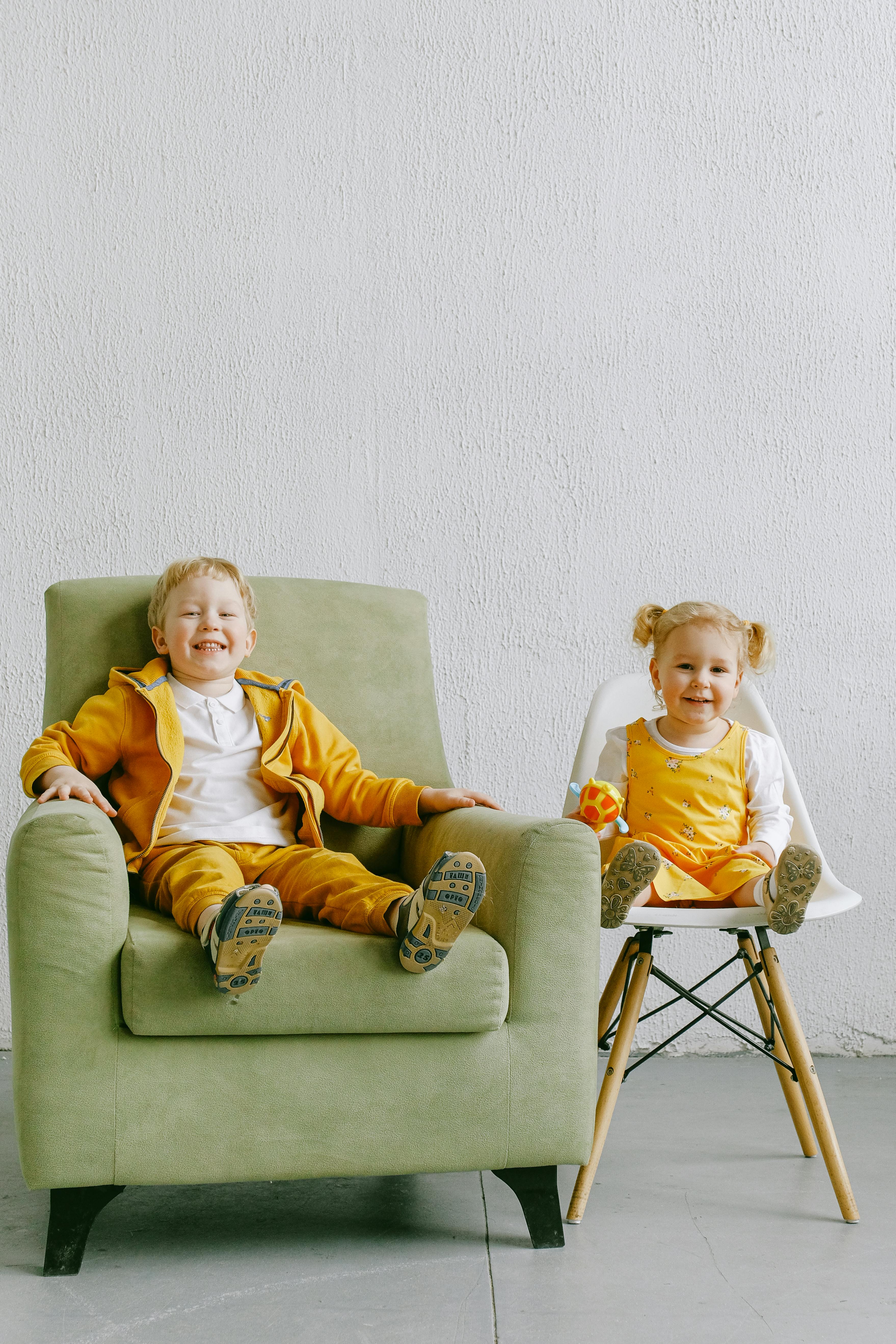 delighted little siblings sitting in living room together