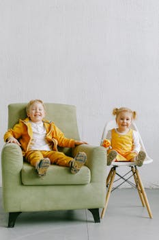 穿着休闲服的可爱男孩和女孩在客厅里，坐在扶手椅和椅子上放松，微笑着看向镜头