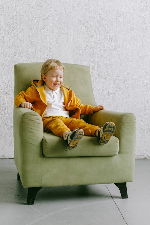 Free Smiling little boy sitting in armchair at home Stock Photo