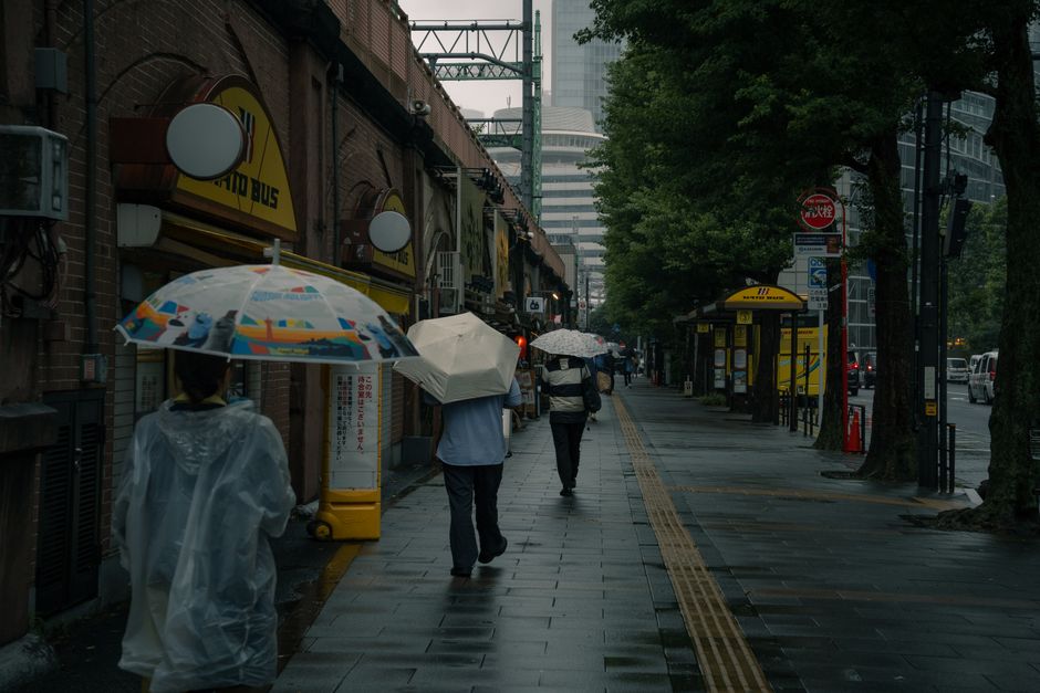People using umbrellas on a rainy street in Tokyo during the Tsuyu season