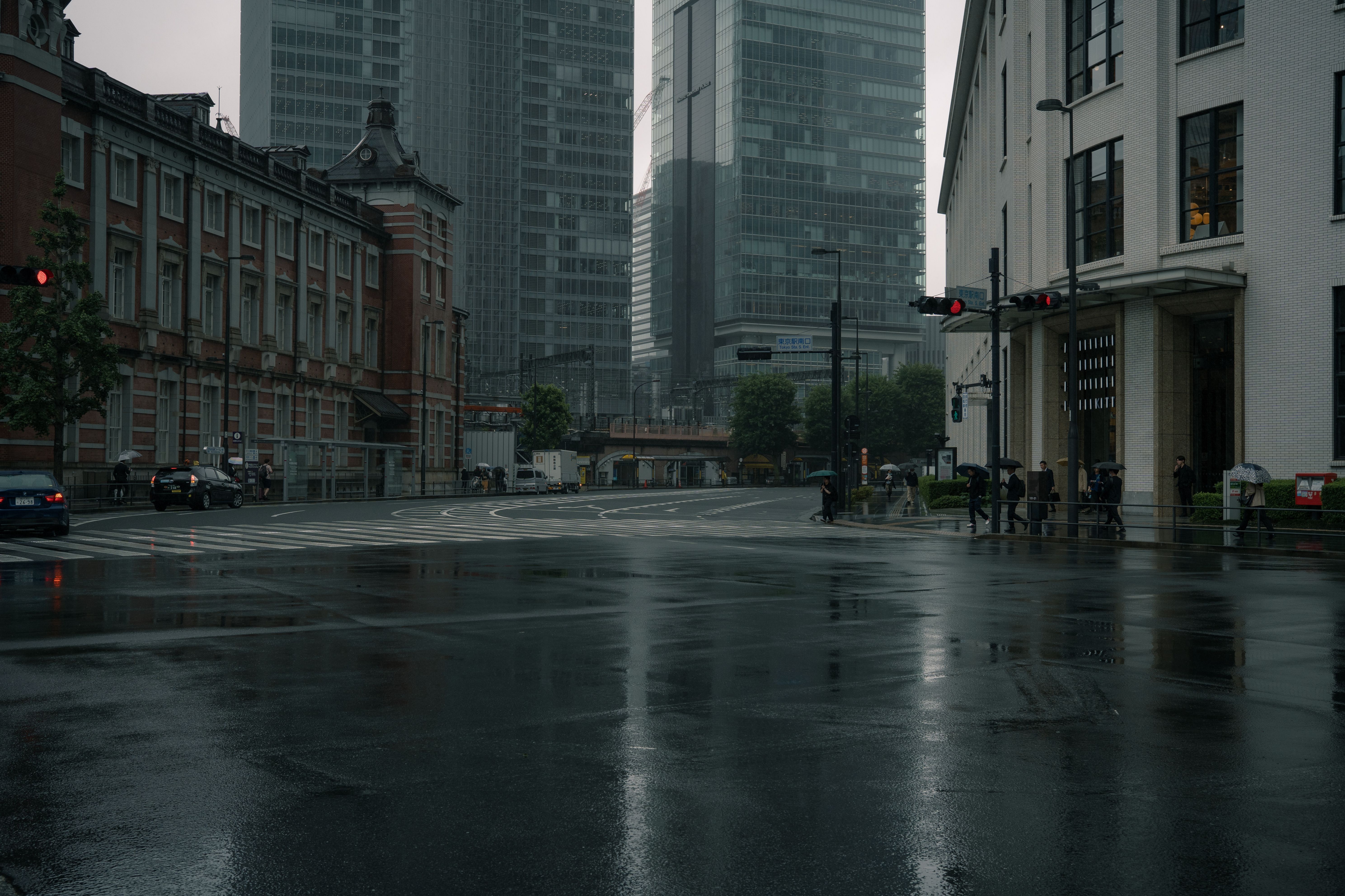高層ビルと濡れた道を特徴とした東京の憂鬱な雨の日、都市生活を捉えています。