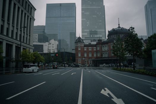 Rainy day street view showing Tokyo Station and modern skyscrapers.