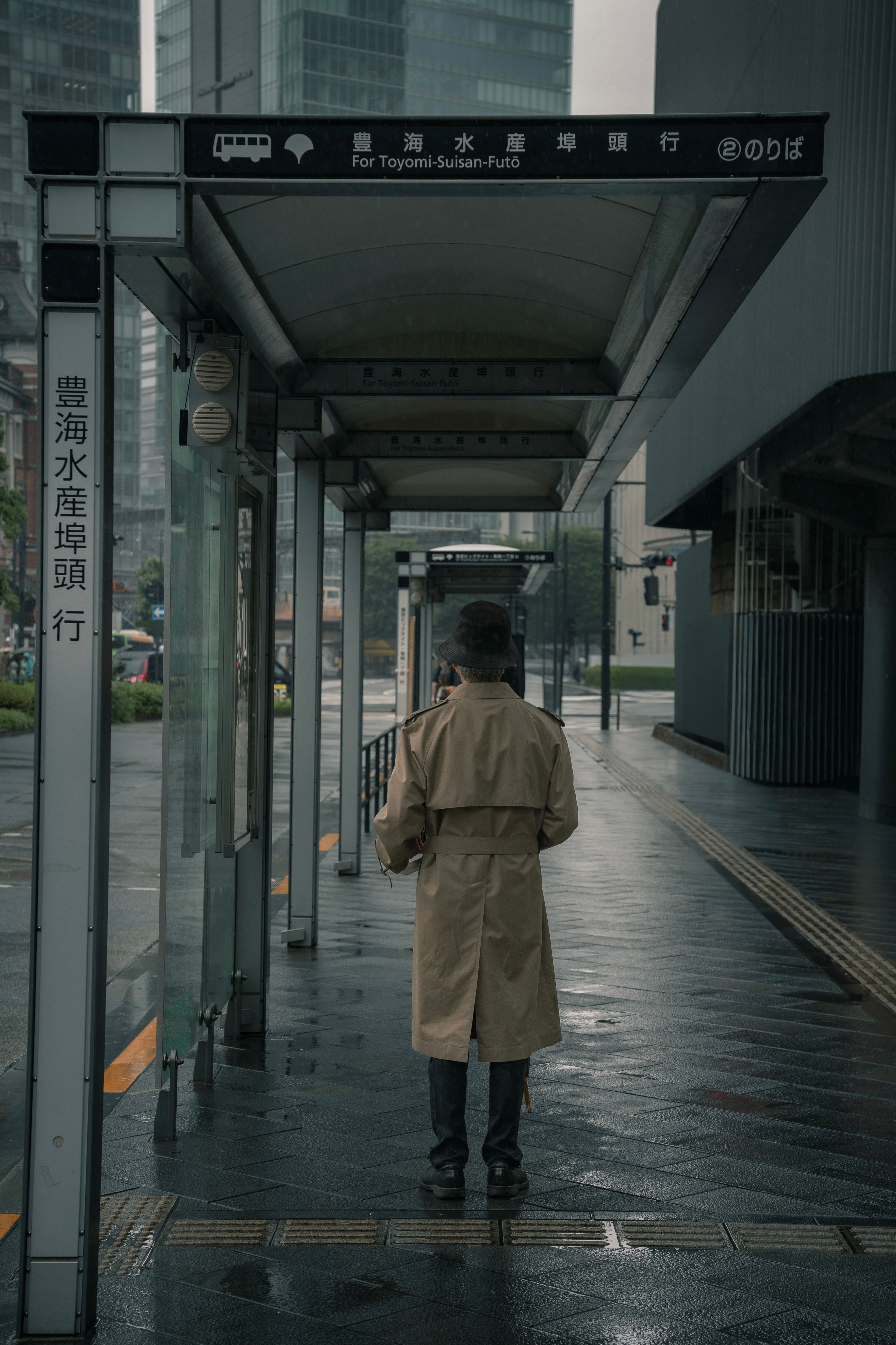 Person in Trench Coat at Tokyo Bus Stop on Rainy Day · Free Stock Photo