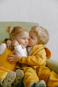 可爱的兄弟姐妹在扶手椅上相拥微笑，捕捉到了爱的温柔瞬间