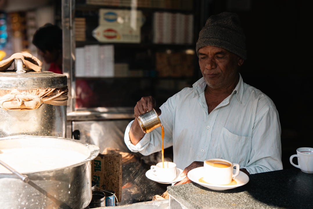 Parsi Cuisine in Gujarat: The Community That Shaped Surat and Ahmedabad's Café Culture 2 A vendor pours steaming chai from a traditional kettle, evoking the tea-and-bun-maska culture of Irani and Parsi cafés