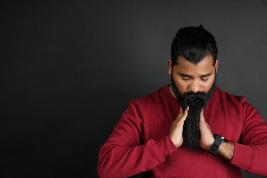 工作室里，一名留着长胡子、穿着红色毛衣的男子正在调整面部毛发的肖像