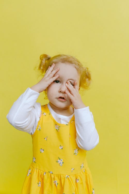 Linda Garota Em Um Vestido Floral Branco E Amarelo Cobrindo O Rosto Com As Mãos