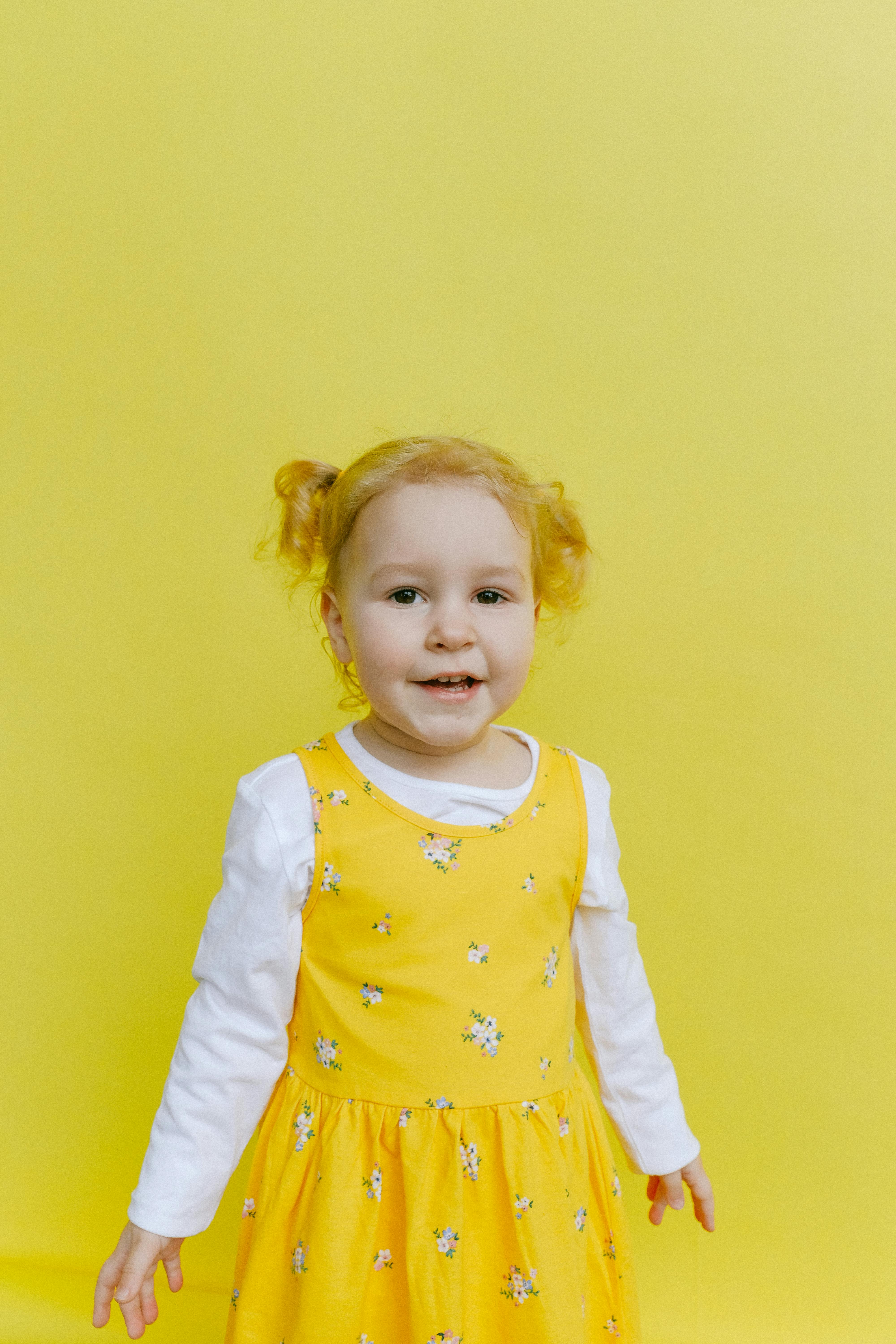 adorable girl standing beside yellow wall