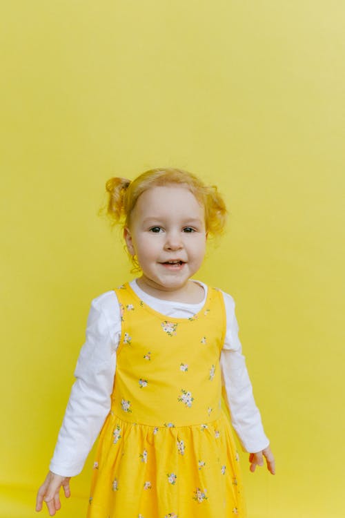 Adorable Niña De Pie Junto A La Pared Amarilla