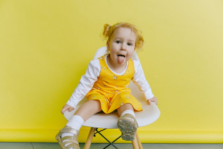 Girl In White And Yellow Long Sleeve Dress Doing Funny Face