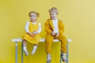 Siblings Sitting On A White Table