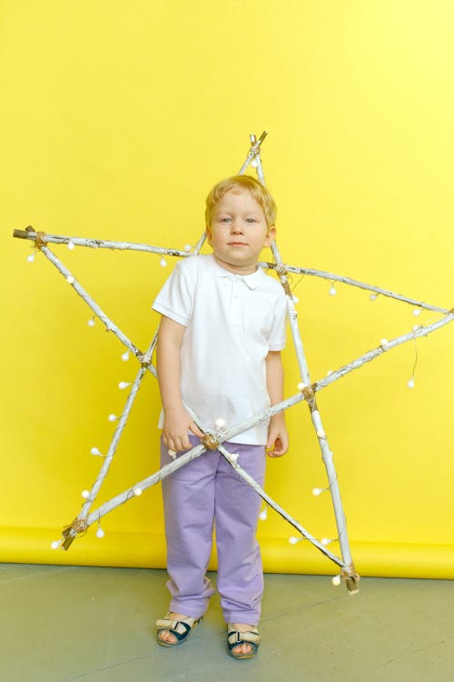 Garçon En Chemise Blanche Et Pantalon Gris Tenant Des Bâtons Encadrés D'étoiles Avec Des Guirlandes Lumineuses