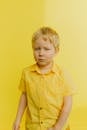 Boy in Yellow Button Up Shirt Standing Near Wall