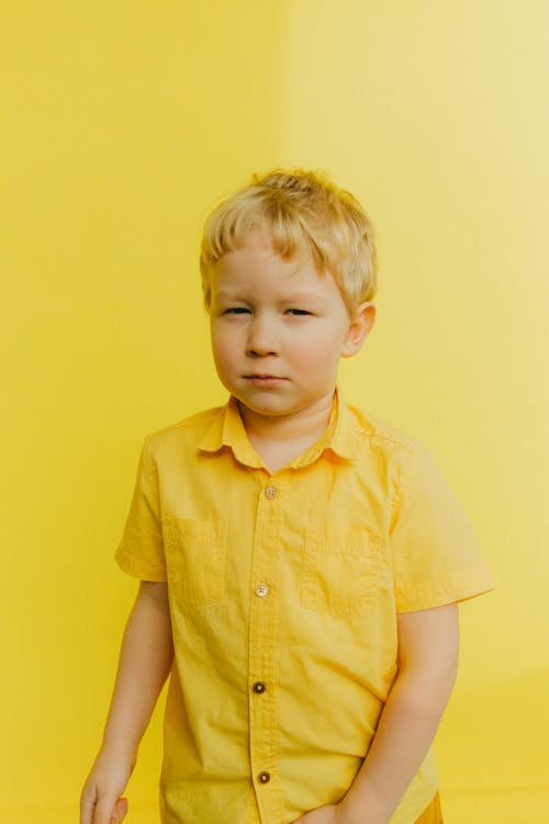 Jongen In Gele Knop Up Shirt Staande In De Buurt Van Muur