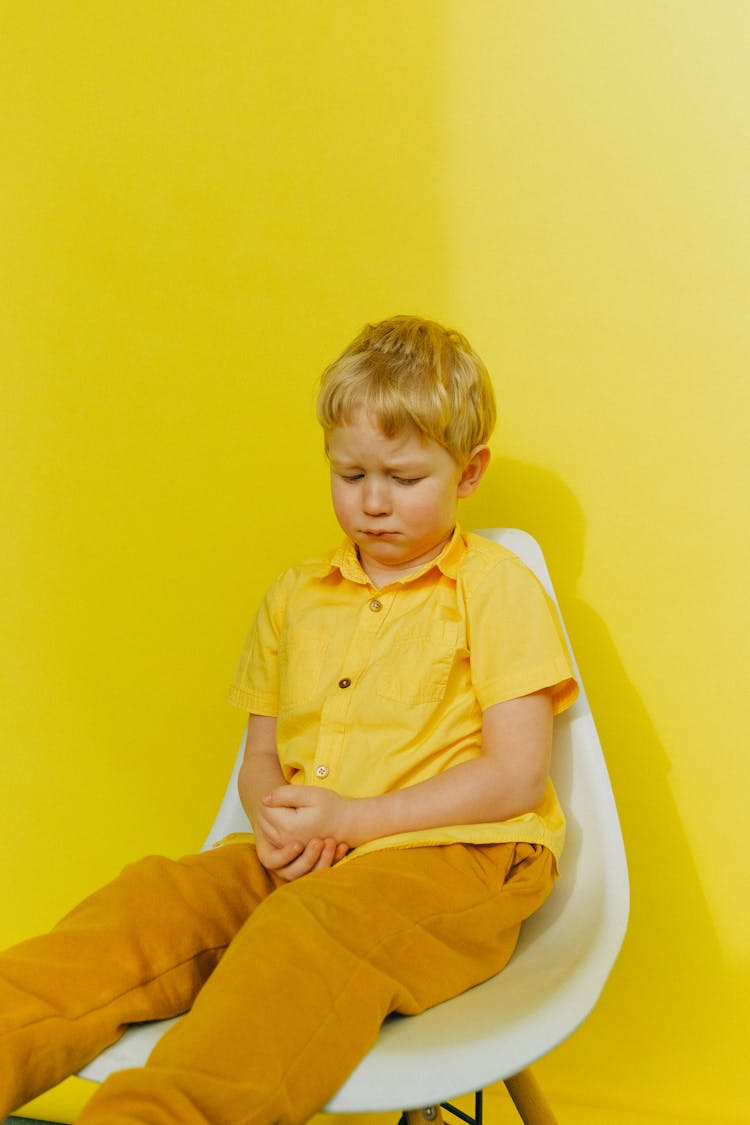 Sad Child Sitting On A White Chair 