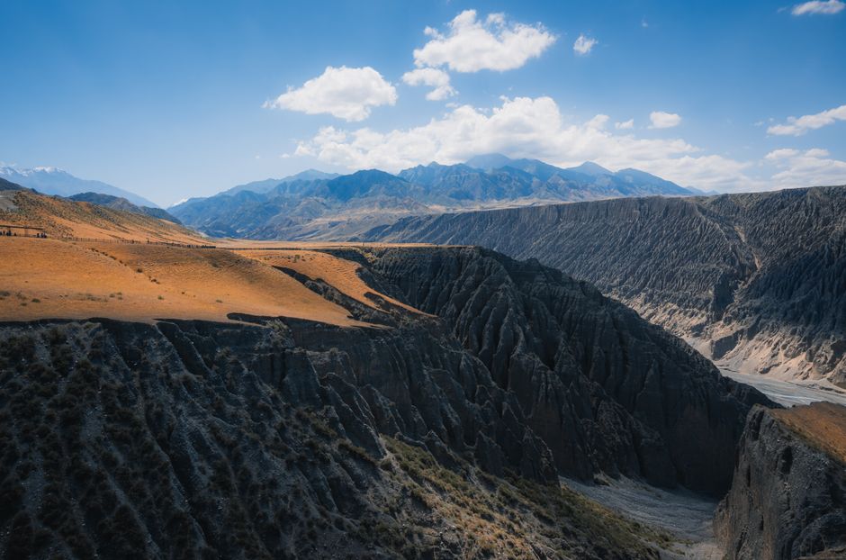 Aerial view of a dramatic canyon with mountains under a bright blue sky.