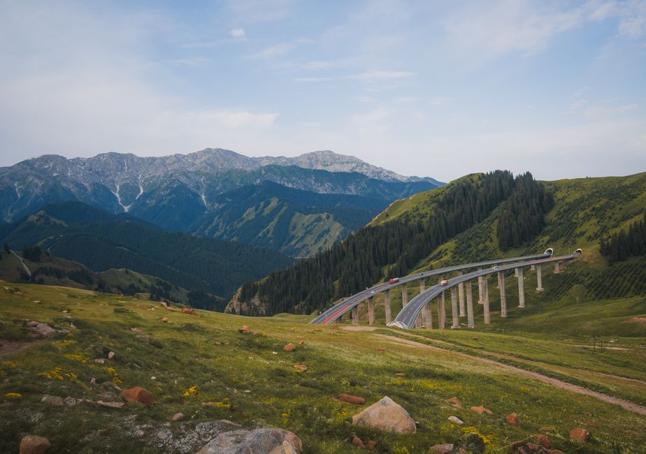 Breathtaking view of a bridge spanning a lush green mountainous region under a clear sky.