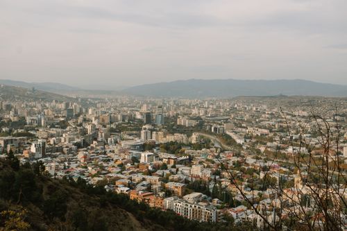 Free Expansive aerial view of Tbilisi city with rolling hills and urban landscape. Stock Photo