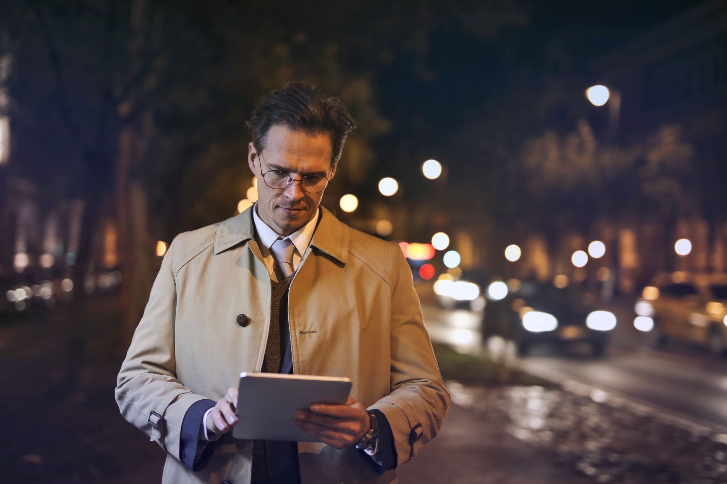Man in a brown overcoat walking on an autumn city sidewalk