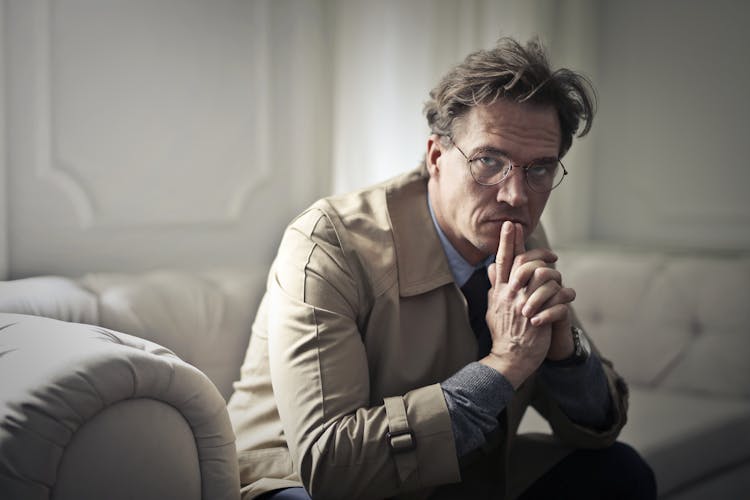 Man In Brown Jacket Sitting On Couch