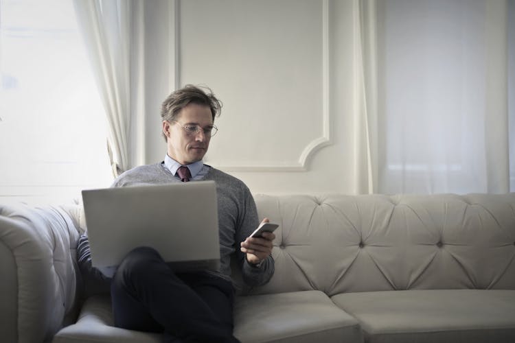 Photo Of A Man Using Laptop And Cellular Phone