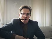 一位时尚的戴眼镜男子在室内抽着雪茄，散发着自信和成熟的气息