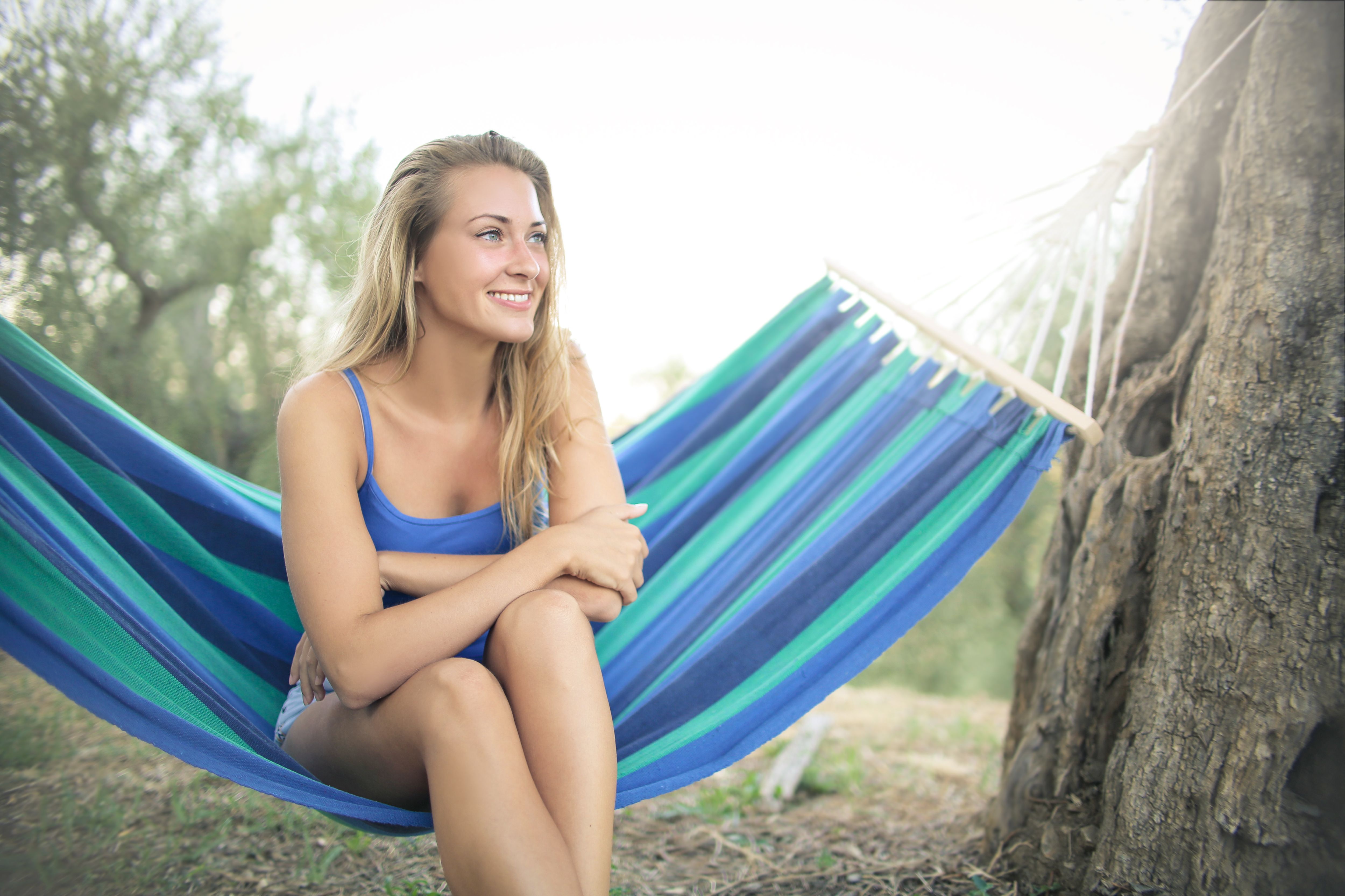 A woman peacefully relaxes in a hammock outdoors, enjoying a bright summer day.