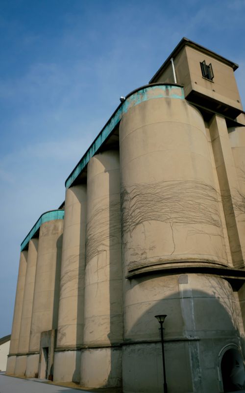 Free Low angle view of industrial silos under a clear blue sky, showcasing aged concrete. Stock Photo