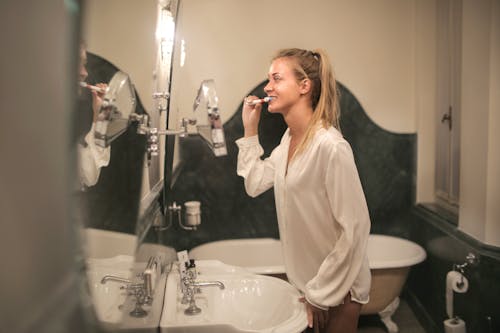 Free Young woman cleaning teeth in bathroom Stock Photo