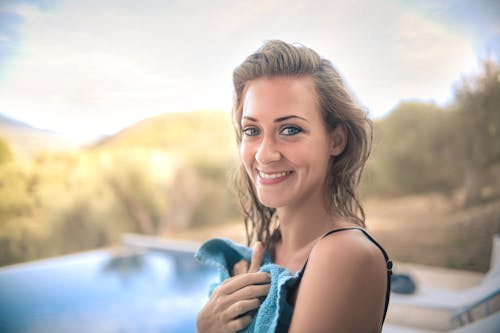 Cheerful woman with towel on poolside