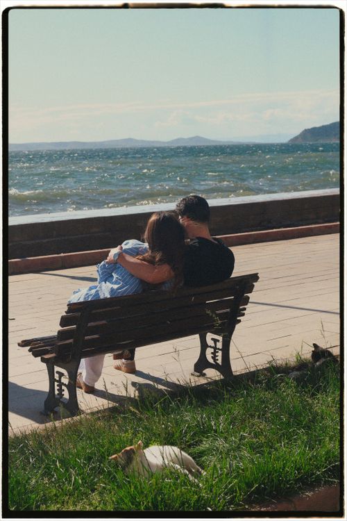 Free A loving couple embraces on a seaside bench, enjoying the view. Stock Photo