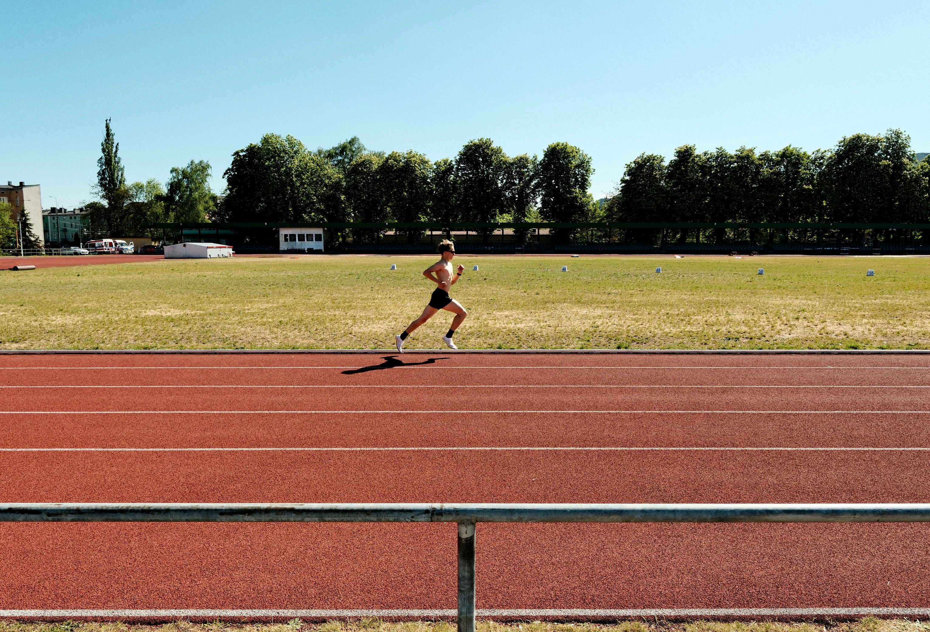 Female athlete running on a sunny day, showcasing speed and endurance on a track.