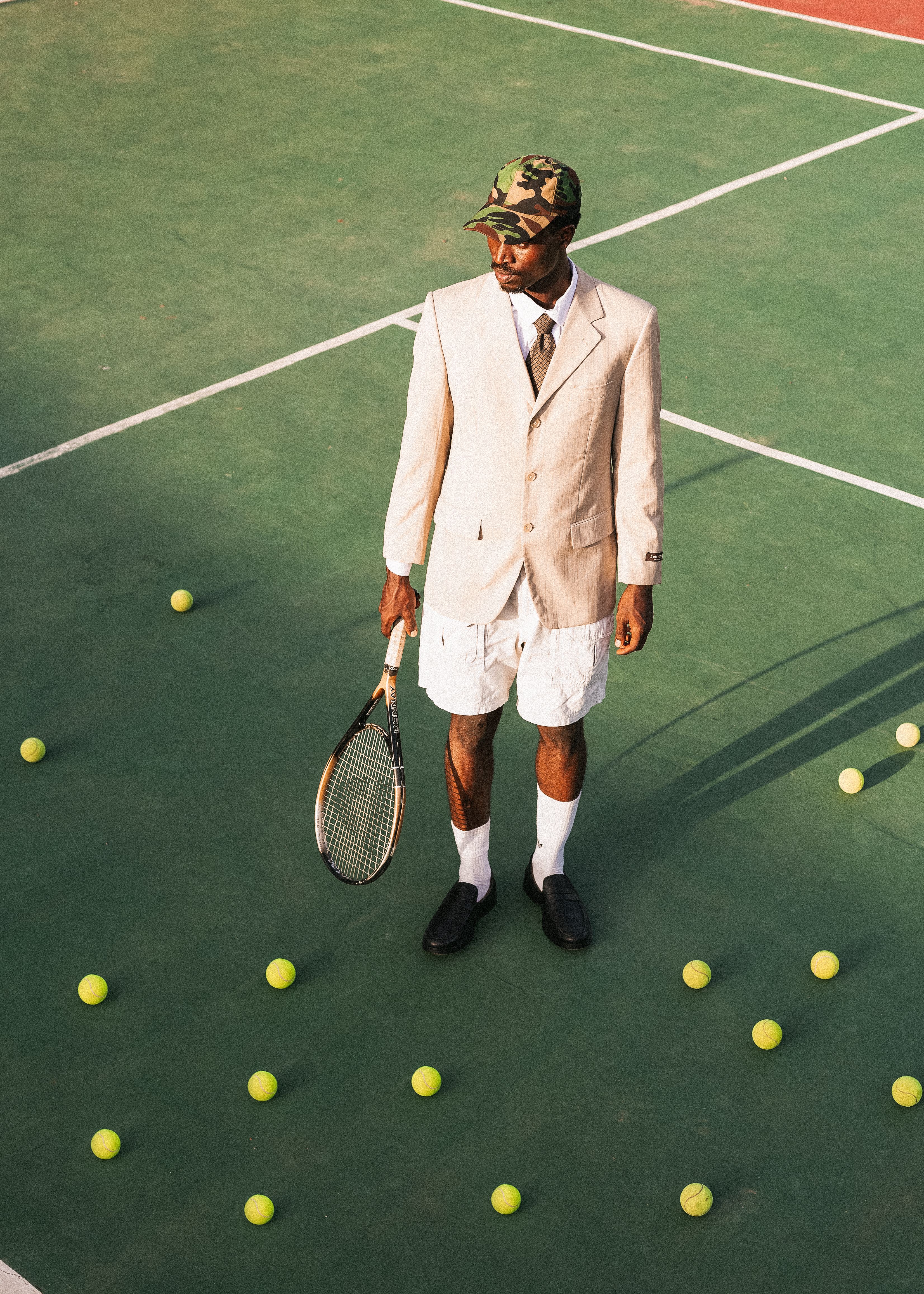 A unique juxtaposition of formality and sport with a man in a suit holding a tennis racket on a court.