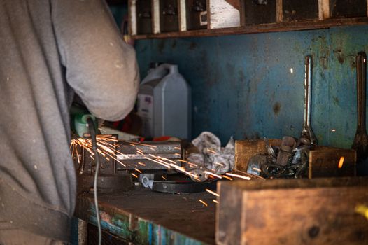 A worker uses an angle grinder, creating sparks in an industrial workshop setting.