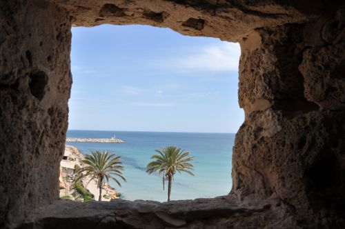 Free View of the Mediterranean Sea through a stone window, capturing the coastal beauty of Tunisia. Stock Photo
