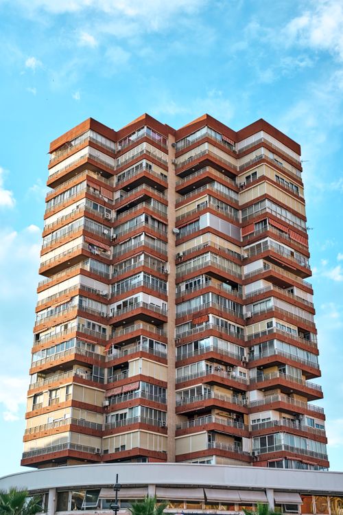 Free A contemporary apartment building showcasing modern architecture under a bright blue sky. Stock Photo