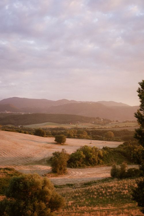 Free Beautiful sunset view over rolling hills with a pastel sky and lush greenery. Stock Photo