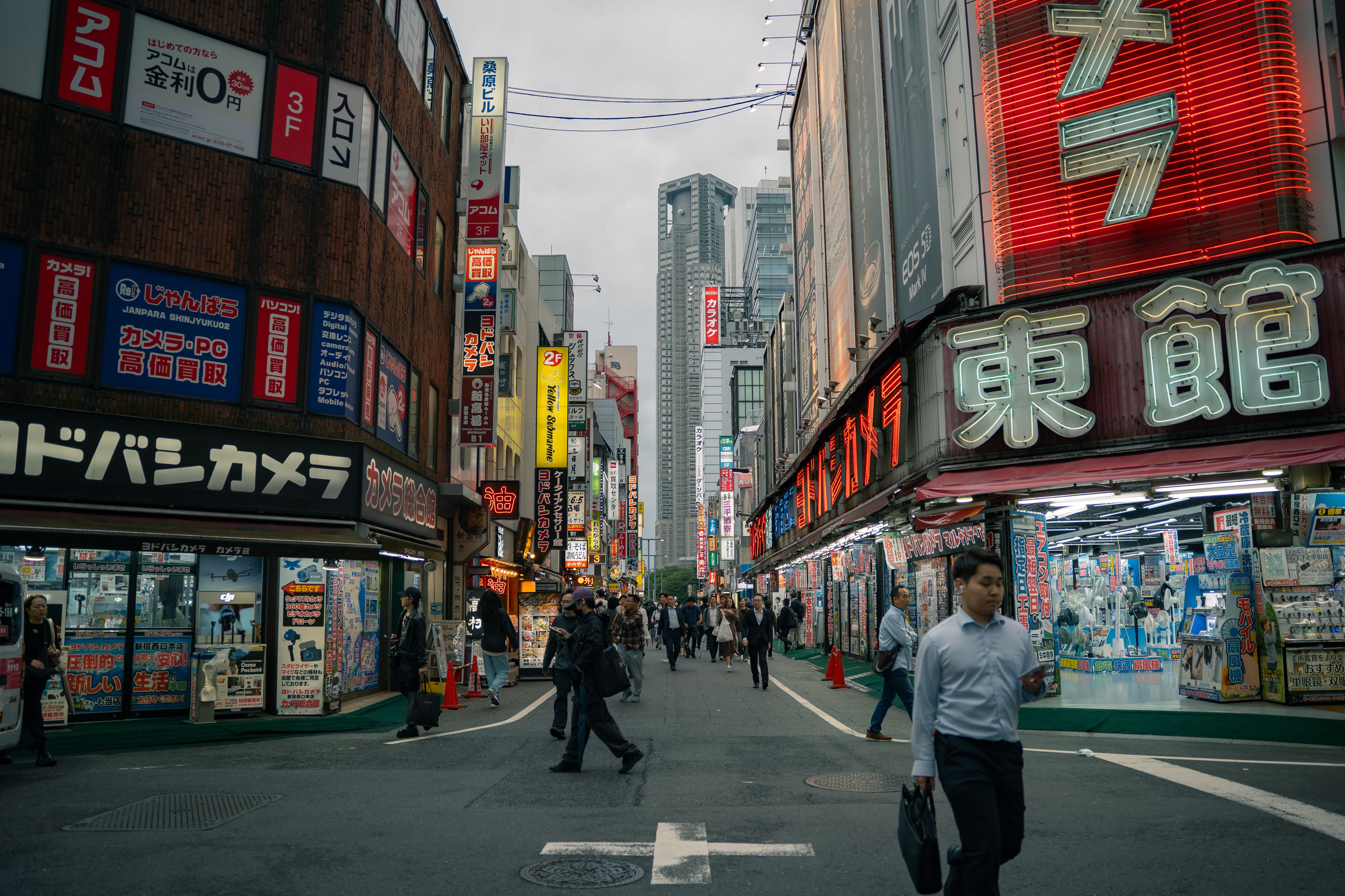 Lively street view in Shinjuku, Tokyo with neon signs and pedestrians.