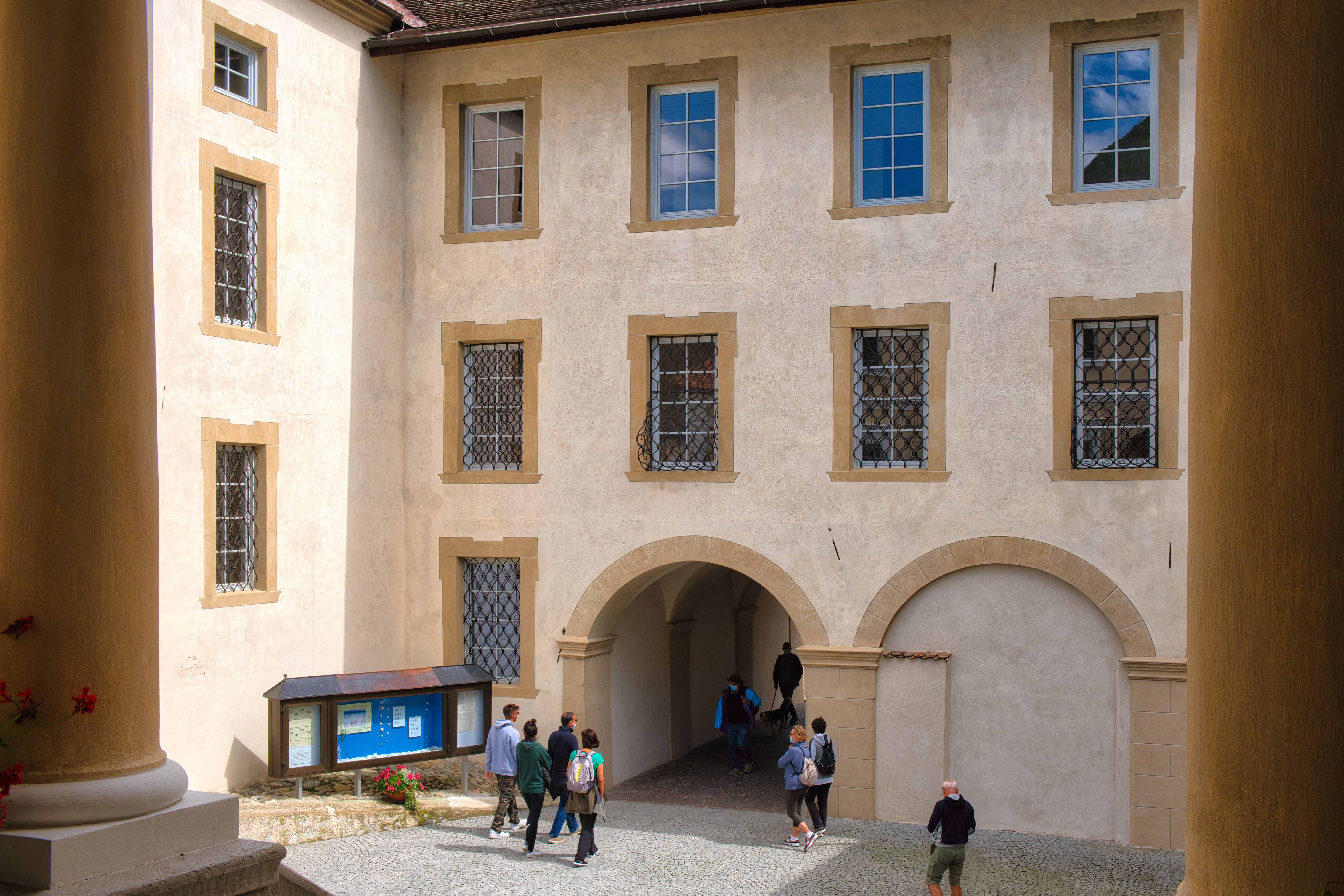 Visitors explore the historic courtyard of Novacella Abbey in Trentino-Alto Adige on a sunny day.
