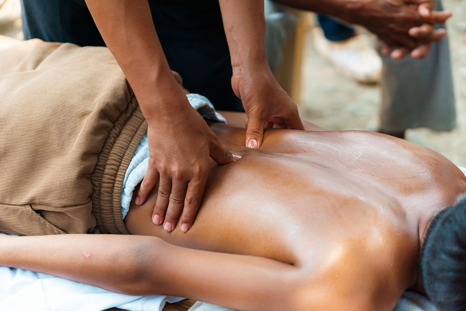 Person standing upright outdoors with hands near the lower back for posture and core support context