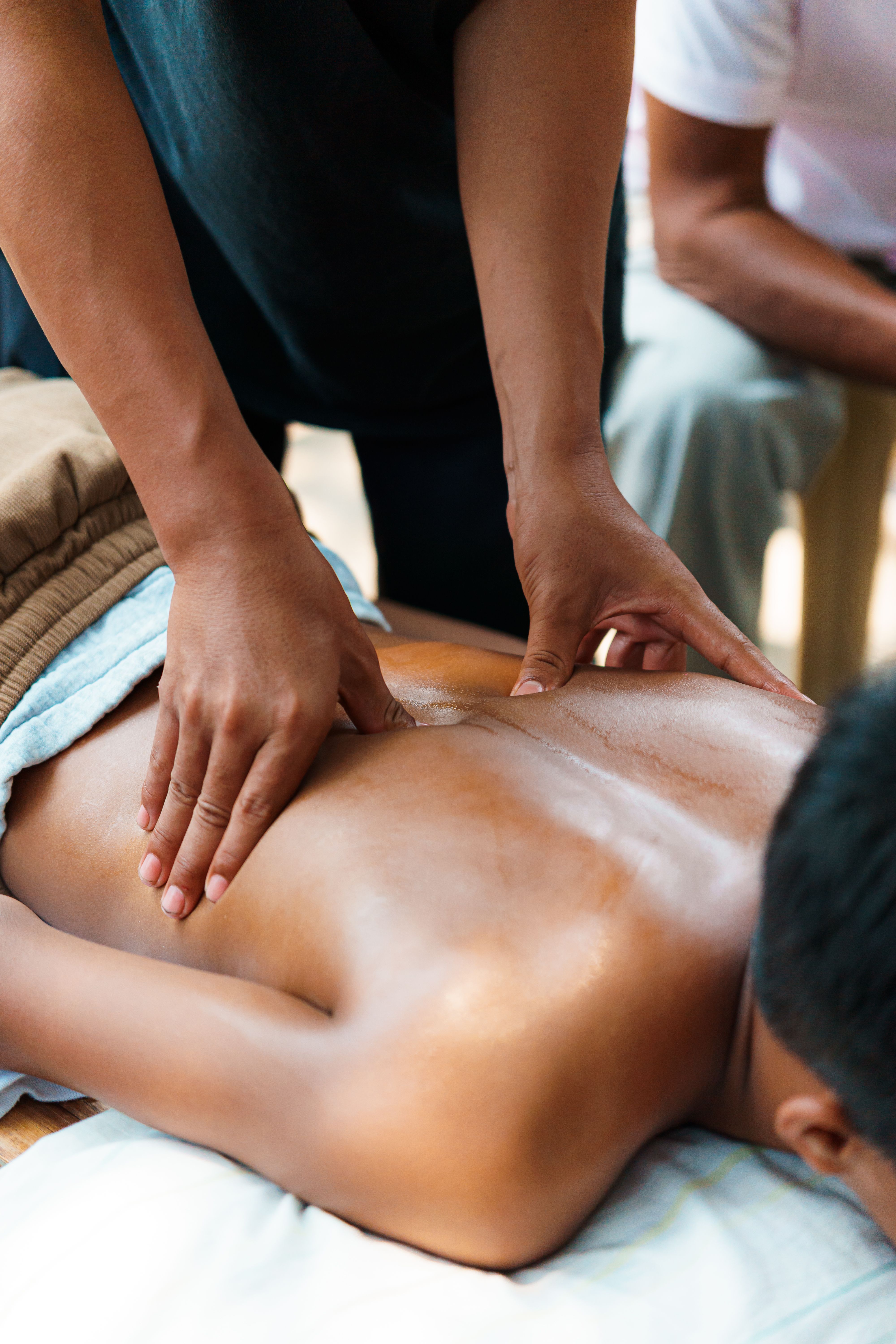 A therapist gently applying massage on a person's back for relaxation and wellness.