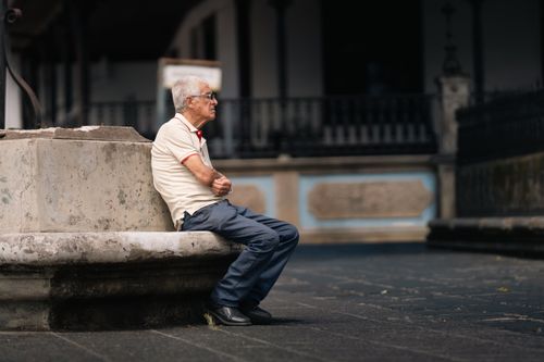 Free A senior adult sitting contemplatively on a stone bench in San José, Costa Rica. Stock Photo