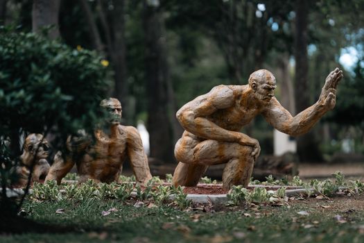Intricate sculptures representing human evolution in a lush San José park.