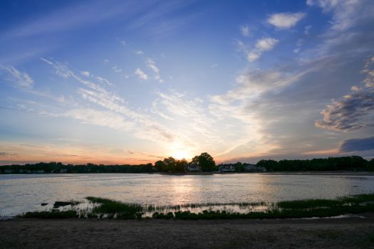 A tranquil sunset over a lake with vibrant colors and dramatic clouds.